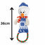 Plush snowman dog  toy with a blue hat, red scarf, and patterned outfit, standing next to a measurement indicator showing its height.