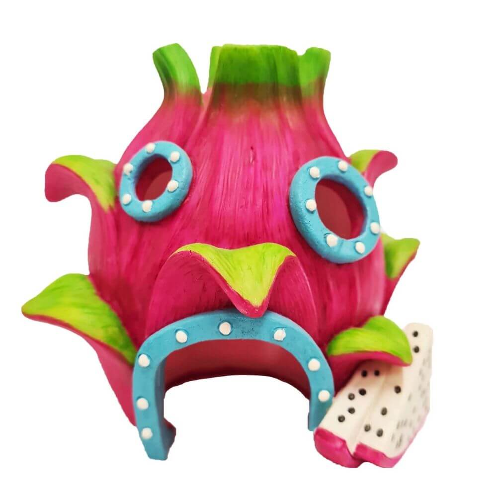 A dragon fruit themed aquarium ornament or shelter, featuring a bright pink body with green scales, blue trim, and a small white-and-pink food piece attached, shown on a plain white background.