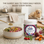 K-9 Sure Super Green Food daily sprinkle container on a kitchen counter with a bowl of dog food and vegetables.