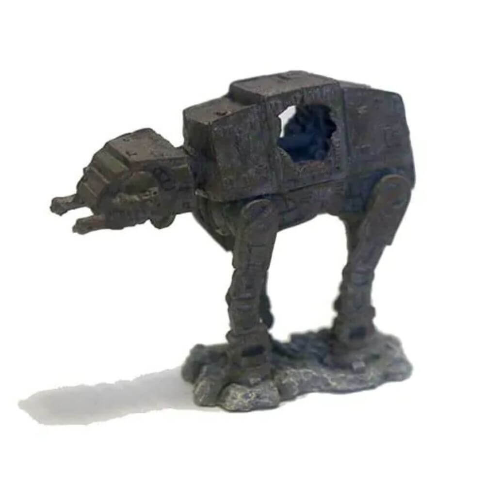 A small dark gray AT-AT walker figurine or miniature toy on a plain white background.