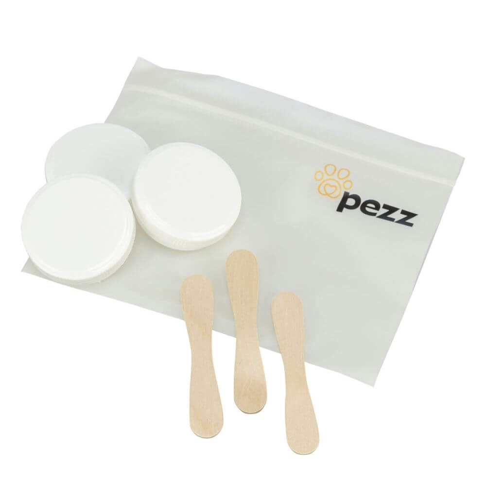 A white plastic zip pouch with the 'pezz' logo, containing three round white lids and three small wooden spatulas, arranged on a white background. Parts of a cat wormer diagnostic kit for sale at PetConnection.ie
