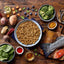 Assorted healthy foods including a bowl of ground meat, vegetables, and fish on a wooden table.