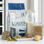 A bag of Red Mills Leader Natural Dog Nutrition Sensitive Adult dog food is displayed on a white countertop with ingredients including rice, dry kibble, wet food, and potatoes in glass jars and on a plate.
