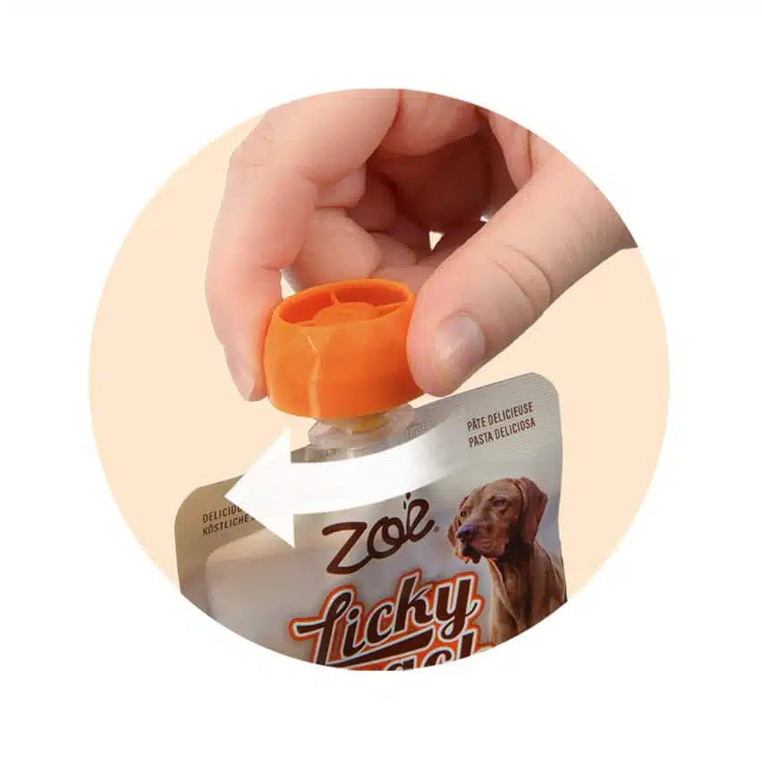 Hand holding a Zolli treat pouch with an orange cap, featuring a dog on the packaging.