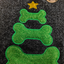 Green bone-shaped Christmas tree with a gold star on a textured black background