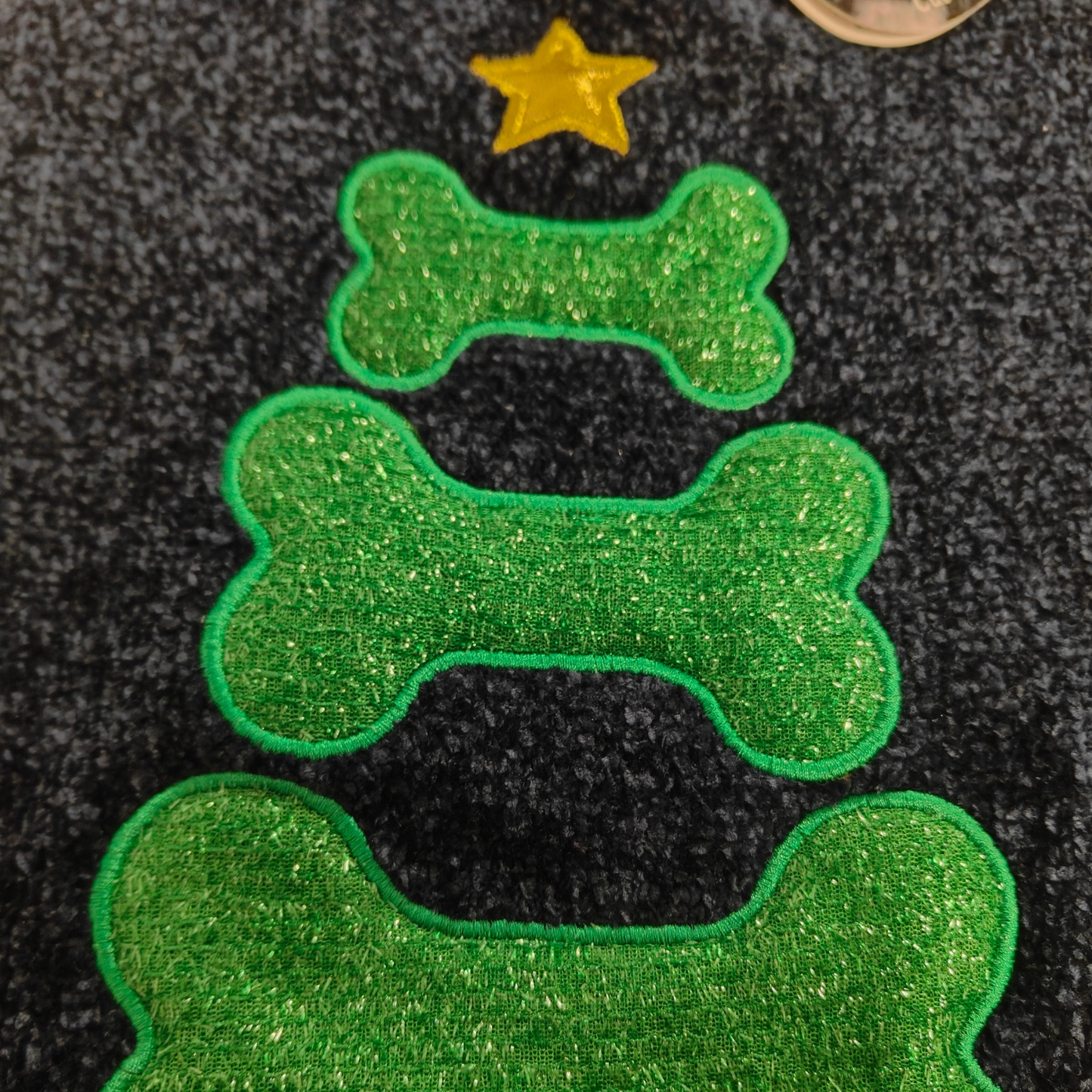 Green bone-shaped Christmas tree with a gold star on a textured black background