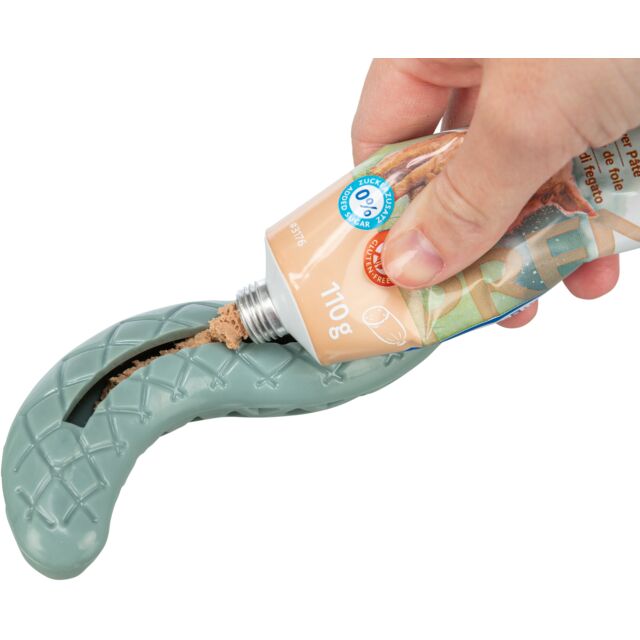 Hand applying a tube of dog treat paste into the slot on the underside of a snake dog toy. 