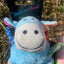 Blue plush toy with a tag labeled 'Hem and Boo' on a grassy background