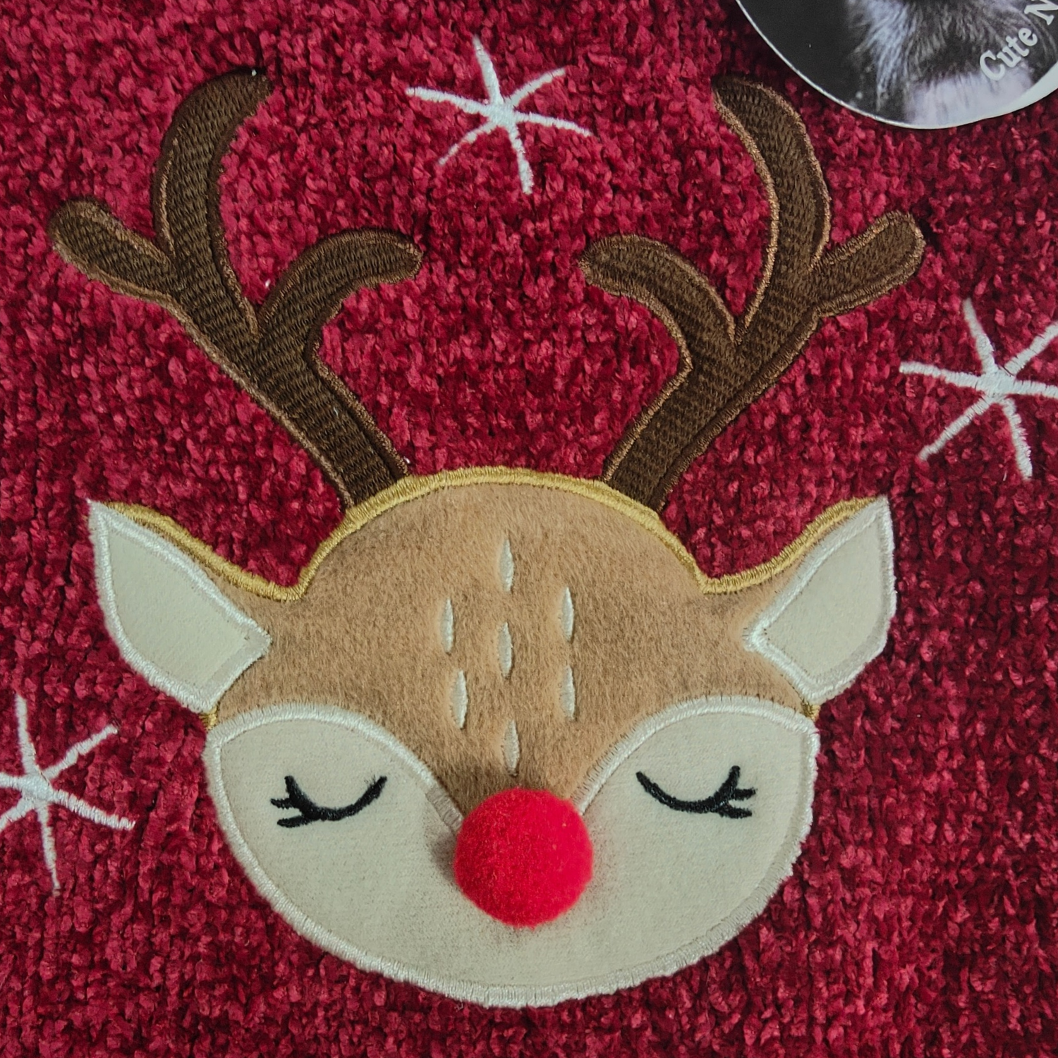 Embroidered reindeer face patch on a red fabric background with white stars