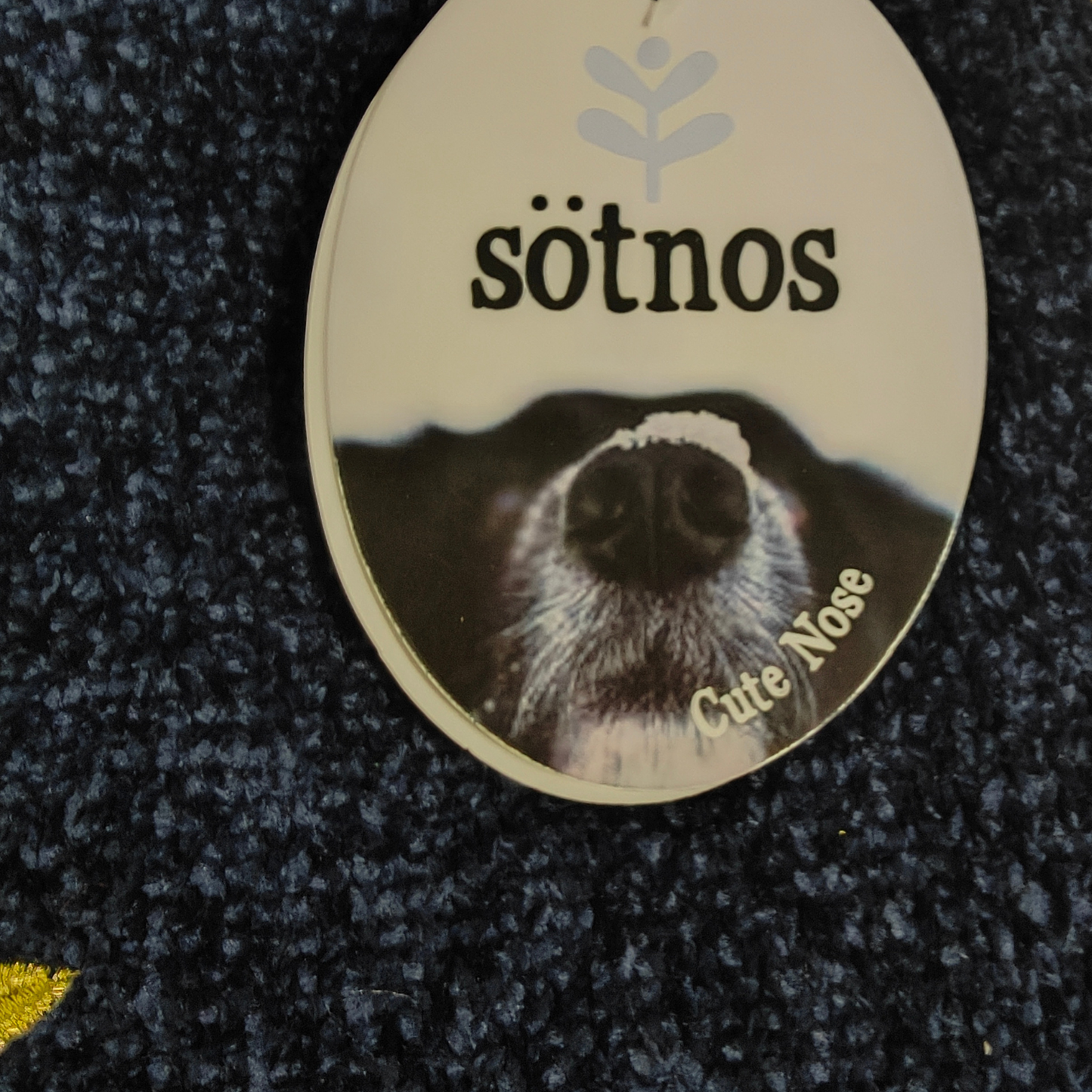 Round sticker with a dog's nose and 'sötnos' branding on a textured black background
