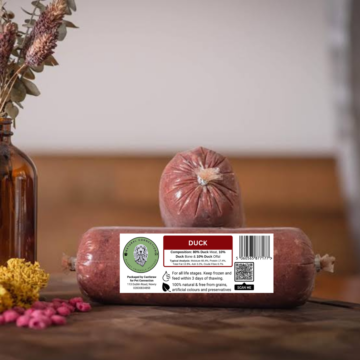 Duck sausage  raw dog food with a label on a wooden surface with decorative elements.