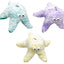 Three plush dog toys shaped like starfish in teal, purple, and yellow on a white background.