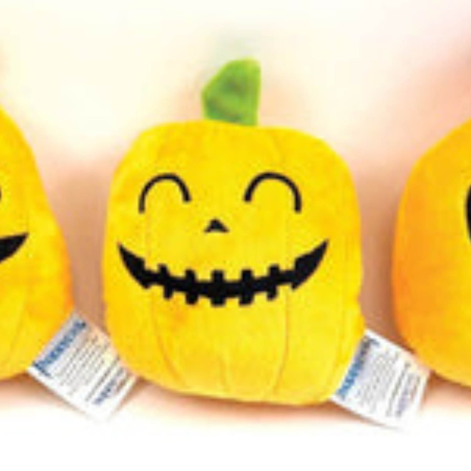 Three plush pumpkin dog toys with smiling faces on a white background