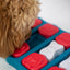 Dog interacting with a puzzle toy with red and white pieces