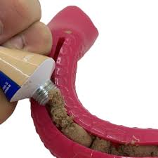 Person applying treat paste into a dog toy