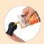 Hand using a pet food pouch with a black scoop to dispense food.